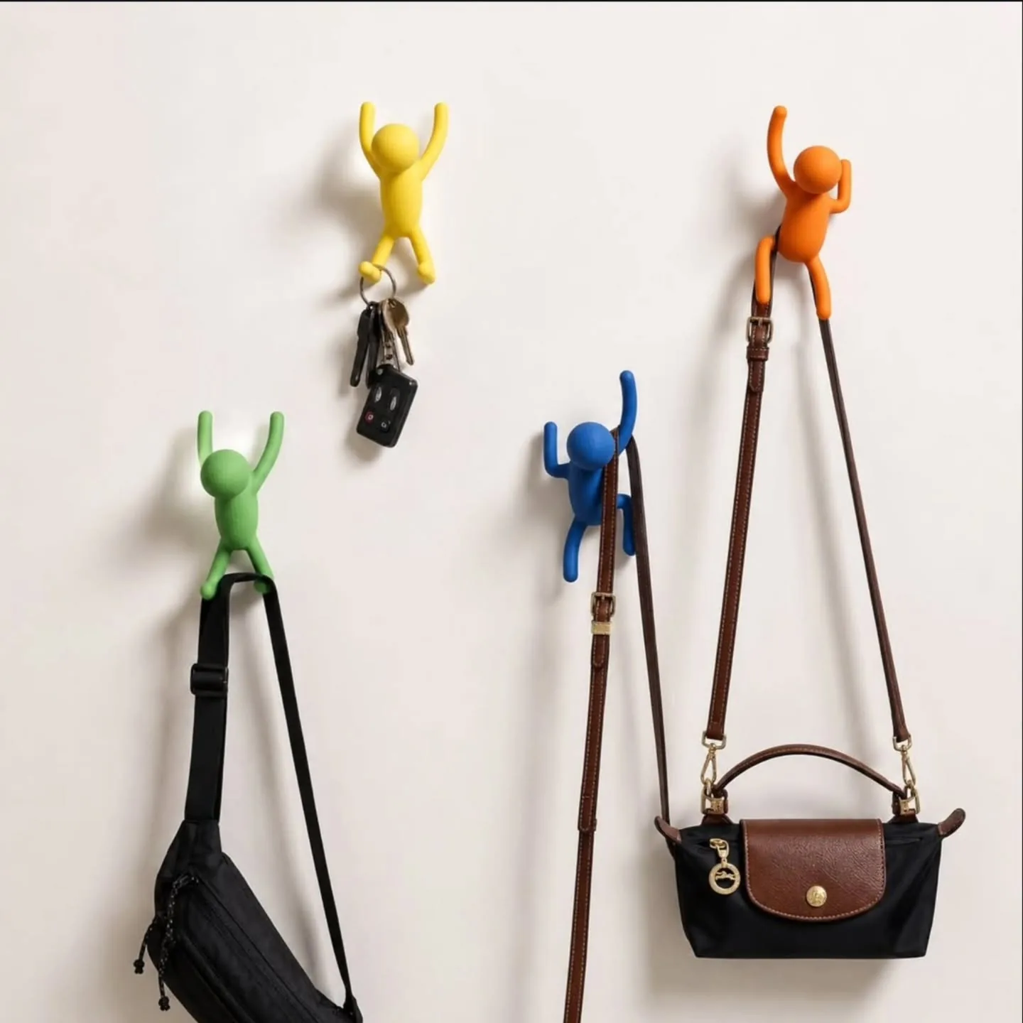Colorful climbing-figure wall hooks holding bags and accessories